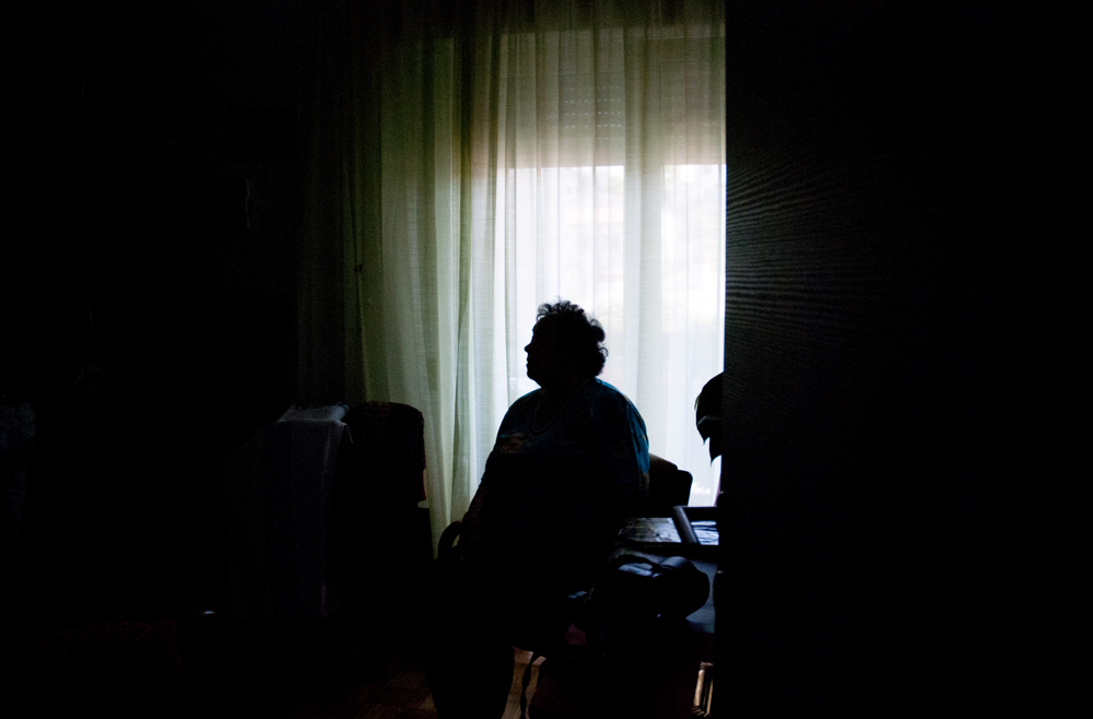 A senior woman sitting in a dark room